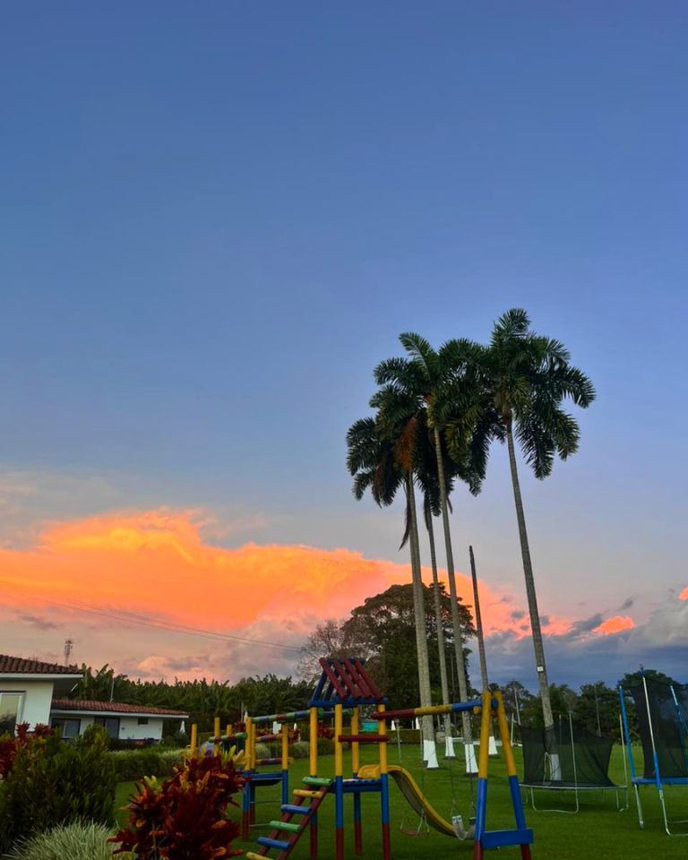 Zona infantil y jardines del Hotel Arrayanes del Quindío durante el atardecer, ideales para disfrutar en familia.
