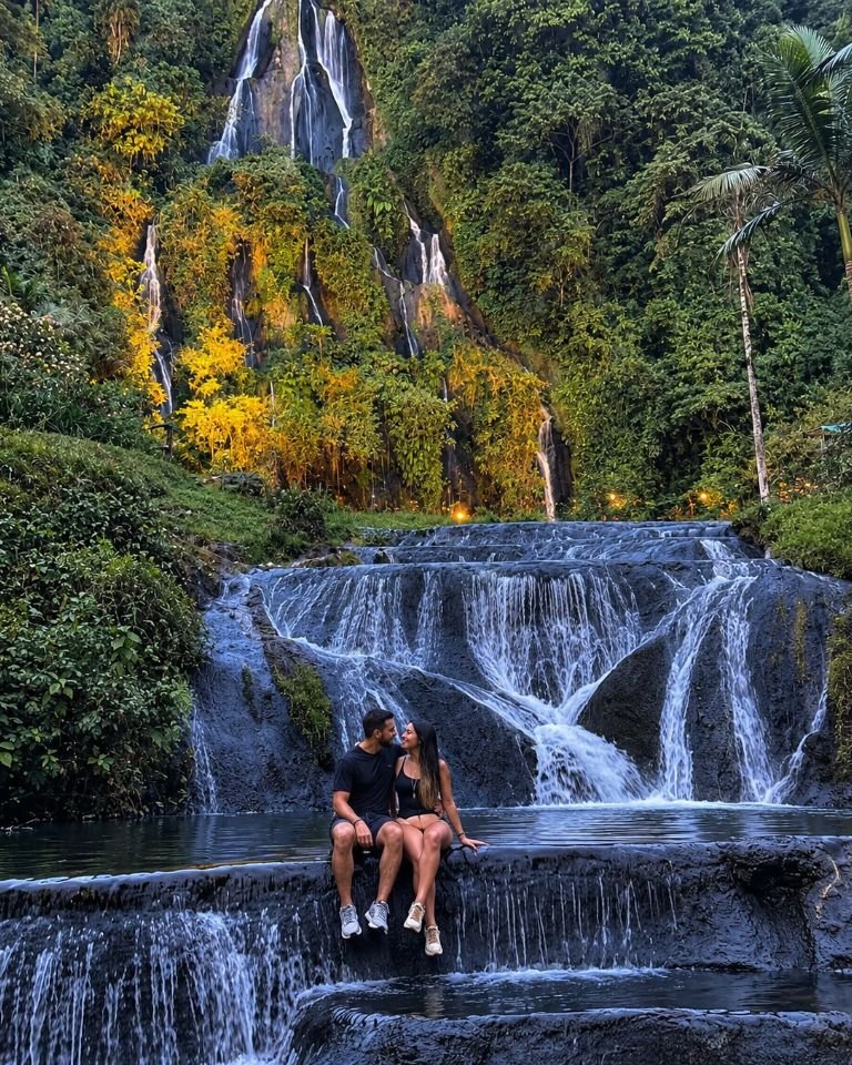 Pareja sentada en las pozas de agua termal frente a la cascada de los termales de Santa Rosa de Cabal, rodeada de bosque